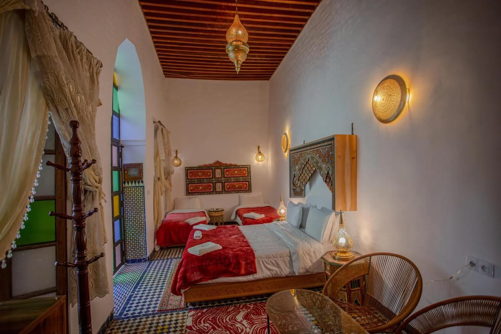 Sitting room with red textiles, carved ceiling and brass lamps